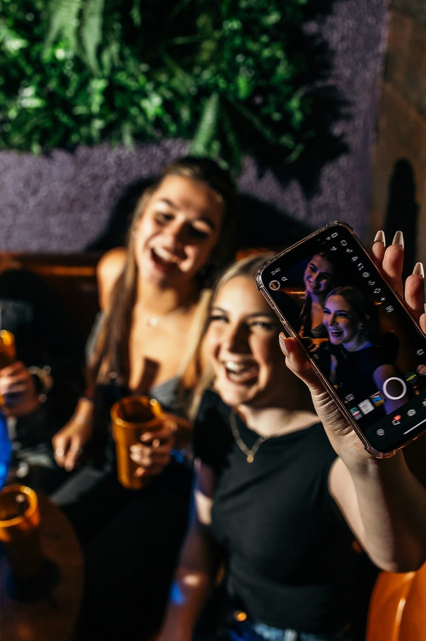 Girls laughing and holding up an iPhone to take a selfie
